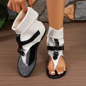Detailaufnahme von weißen Zehentrenner-Sandalen mit Schlangenmuster und schwarzen Schnallen