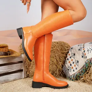 Detailansicht der leuchtend orangefarbenen kniehohen Lederstiefel in rustikaler Wüstenszene