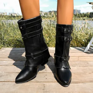 Close-up view of black pointed-toe Martin boots with buckle straps in outdoor setting.