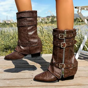 Detailed view of brown slouchy boots with buckles and chunky heels on a wooden deck.