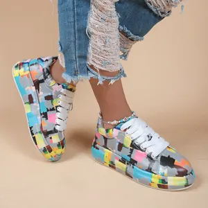 Detailed view of colorful graffiti platform sneakers worn with ripped jeans on a model.