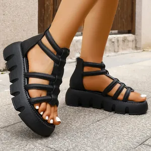 Detailweergave van zwarte platform gladiatorsandalen met getextureerde bandjes op straat