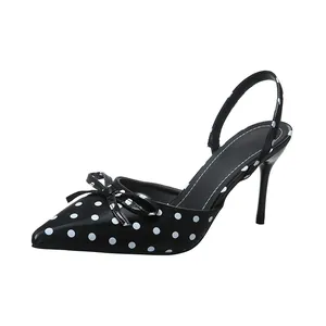 Detalle lateral de elegantes zapatos destalonados negros con lunares blancos y lazo
