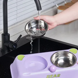 Detachable stainless steel pet bowl being rinsed under kitchen faucet detail view