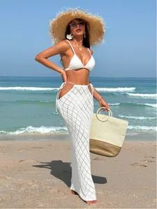 Close-up of elegant white knit hollow-out long beach skirt featuring sexy side ties