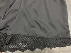 Vue détaillée montrant la délicate bordure en dentelle et la texture du tissu noir du short.