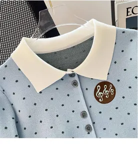 Detail view of polka dot knit cardigan with white collar and embroidered musical note badge