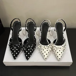 Elegantes zapatos de tacón con lunares y detalle de lazo en blanco y negro.