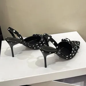 Tacones negros con lunares estilo francés con lazo elegante y correa en una caja blanca