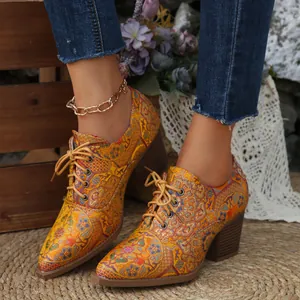 Vista dettagliata di scarpe con tacco in raso ricamato vintage e motivi floreali.