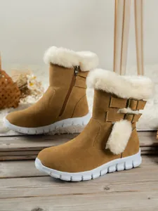 Close-up of brown suede snow boots with white faux fur lining and pom-pom detail.