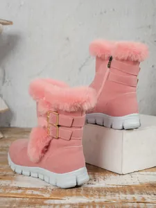 Detailed macro view of pink suede snow boots featuring plush fur trim and gold buckles