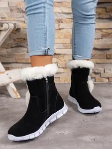 Close-up of women's black snow boots with white plush fur trim and platform sole.