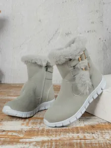 Detail of grey women's snow boots with plush lining and golden buckle decorations.