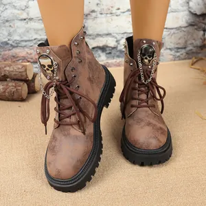 Détail de bottes de combat marron vintage à plateforme avec crâne et chaîne en métal.