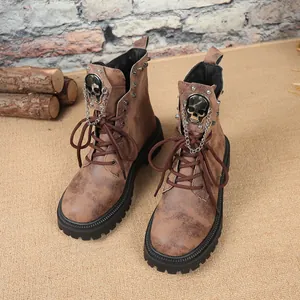 Détail de bottes punk vintage marron avec emblèmes tête de mort et chaînes de métal