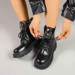 Gros plan de bottines Martin noires punk avec détails de tête de mort et de chaînes.