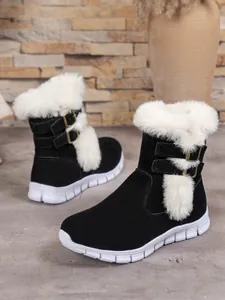 Detailed view of women's black snow boots with plush white fur and buckle straps