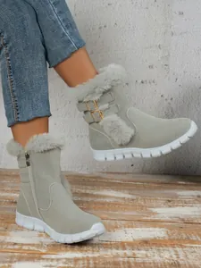 Grey women's snow boots with faux fur trim and gold buckle detail on wooden floor