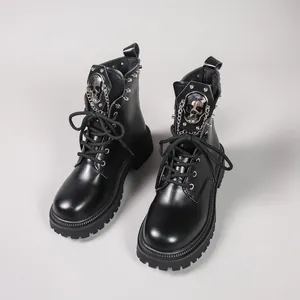 Détail de bottes punk à plateforme noires avec emblème de crâne et chaîne métallique