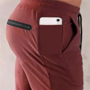 Close-up of side phone pocket and zipper back pocket on men's burgundy joggers