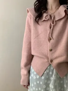 Close-up of pink knitted cardigan with doll collar and decorative heart-shaped buttons.