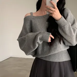 Primo piano di un maglione grigio con spalla scoperta e rifiniture a coste chic.