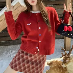 Red knit cardigan with dog embroidery and colorful buttons worn in a snowy scene.