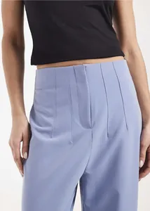 Close-up detail of light blue high-waisted trousers showing vertical stitched pleats