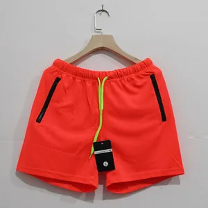 Detalle de pantalones cortos deportivos naranja neón con bolsillos con cremallera