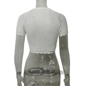 Dettaglio di un top corto bianco in maglia traforata a maniche corte con bordi smerlati