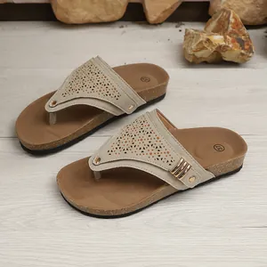 Detailed view of beige wedge flip-flops featuring laser-cut patterns and metal studs.