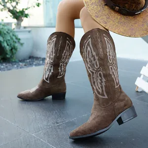 Detailansicht brauner Wildleder-Cowboystiefel mit weißer Stickerei und Blockabsatz.