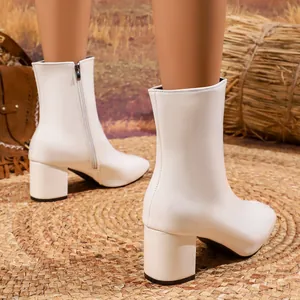 Close-up detail of white pointed-toe ankle boots with a stylish block heel.
