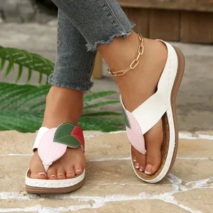 Detalle de chanclas de cuña para mujer con un diseño de tira en forma de hoja colorida.