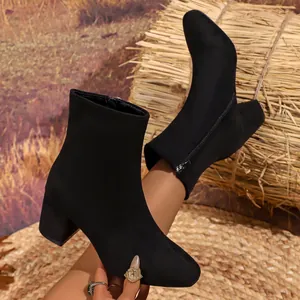 Close-up detail of stylish matte black ankle boots with side zipper and stable block heel