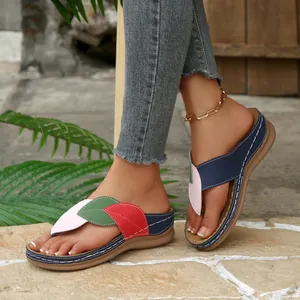 Detalle de chanclas de cuña para mujer con tiras de hojas coloridas y base azul marino