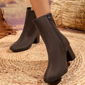 Close-up of brown suede ankle boots featuring side zipper, pointed toe and block heel