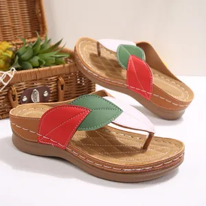 Detalle de sandalias de cuña para mujer con diseño de patchwork de hojas de colores.