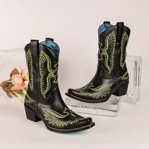 Détail de bottes de cowboy noires avec broderie d'aigle vert néon et bout pointu