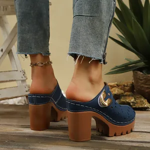 Close-up of navy platform clogs with golden heart buckle and laser-cut floral details