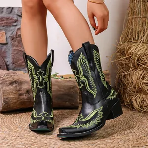 Vue détaillée de bottes de cowboy noires avec broderies vertes et bout pointu.