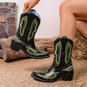 Détail de bottes de cowboy vintage noires avec broderie vert citron et bout pointu.