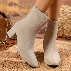 Close-up of beige suede pointed toe ankle boots with block heel and side zipper