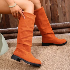 Detail of orange slouchy tall boots with suede-like texture and comfortable flat sole
