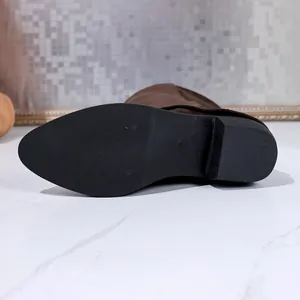 Detailed view of the anti-slip black sole and sturdy block heel of a brown suede boot