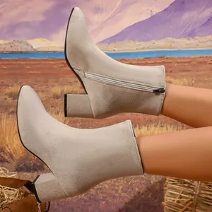 Detail of beige pointed-toe suede ankle boots with block heel and side zipper.