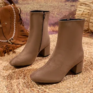 Brown suede block heel ankle boots with side zipper shown in a rustic outdoor setting