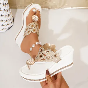 Close-up of white platform flip-flops with ornate rhinestone and pearl embellishments