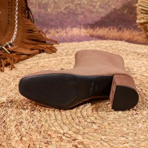 Detailed macro view of a brown suede short boot sole with block heel on a woven mat